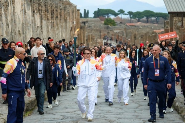 Actor Jackie Chan holds the olympic torch passing through the Archaeological Park in Pompeii. Photo: AP