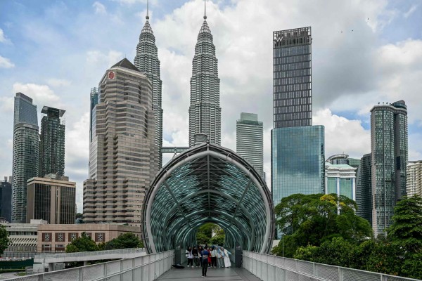 Tourists take pictures with Malaysia’s Petronas Twin Towers in the background in Kuala Lumpur. The country aims to attract 47 million international visitors during the Visit Malaysia 2026 campaign. Photo: AFP