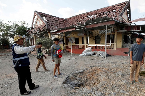 People stand beside a crater in front of a damaged police station following clashes between Cambodian and Thai soldiers in Banteay Meanchey province, Cambodia on Saturday. Photo: AFP