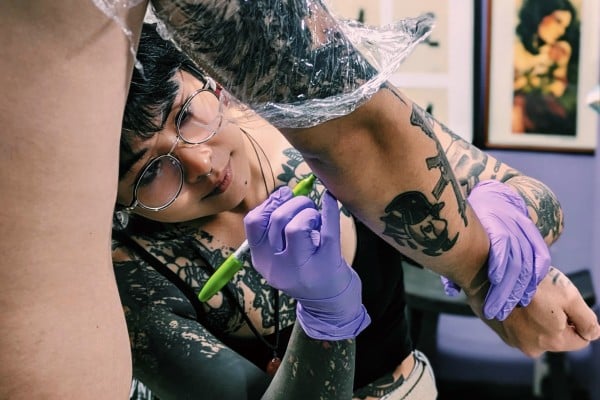 Bella Yuen tattoos a client at her Hong Kong studio. The artist, who is greatly influenced by Chinese calligraphy and painting, is one of a group in the city taking inspiration from traditional elements to create something new. Photo: Nic Tse