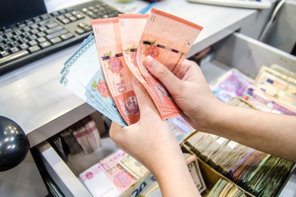 A woman counting several notes of the Malaysian ringgit. The currency has risen against the Singapore dollar in recent trading sessions. Photo: Shutterstock 