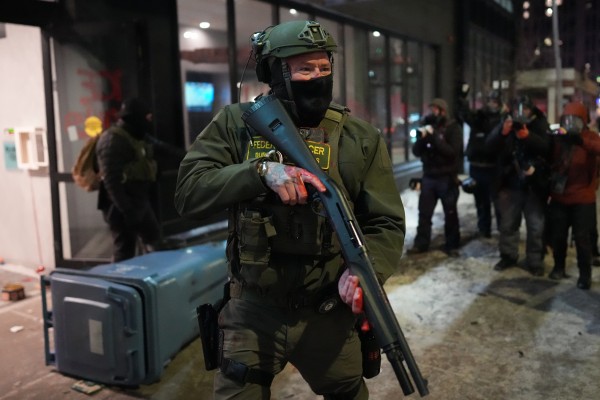 A federal agent stands guard near a hotel during a protest against immigration enforcement operations in Minneapolis. Photo: AP