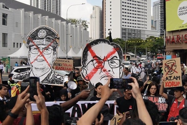Malaysian protestors carry placards with the faces of MACC head Azam Baki (left) and Prime Minister Anwar Ibrahim on Sunday. Photo: X/Rafizi Ramli