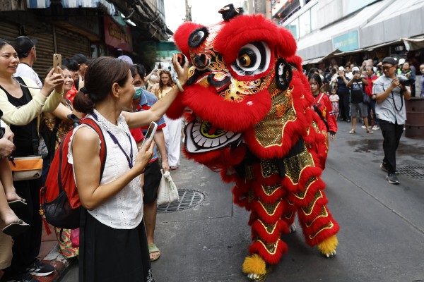 A tourist interacts with a lion dance performer in Bangkok’s Chinatown, Thailand, on Monday. Photo: EPA
