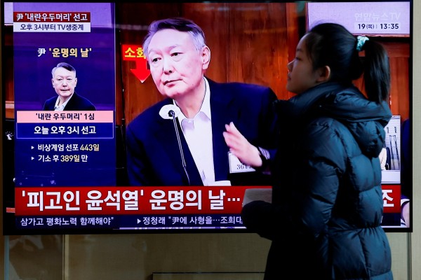 A woman walks past a television screen in Seoul broadcasting a news report on Yoon Suk-yeol’s sentencing on Thursday. Photo: Reuters