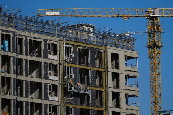 Workers install insulation on a residential building under construction in Beijing in December. Photo: AP Workers install insulation on a residential building under construction in Beijing in December. Photo: AP