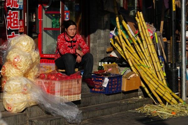 A vendor sits at the doorway to her store in Beijing on February 18. China’s leadership is pivoting towards people-centric, consumption-led economic growth. Photo: Getty Images