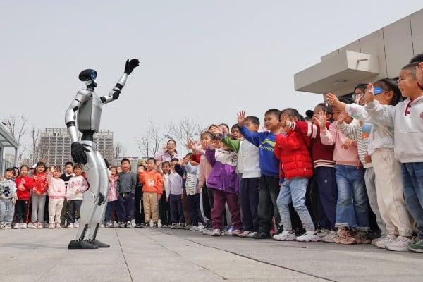 A humanoid robot waves to children at a kindergarten in China’s eastern Shandong province. Photo: Getty Images