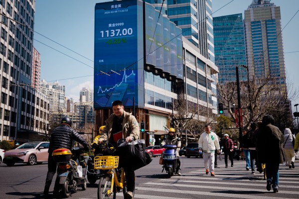 People cross the street beneath a screen showing stock exchange data in Shanghai on March 9, 2026. Photo: EPA People cross the street beneath a screen showing stock exchange data in Shanghai on March 9, 2026. Photo: EPA