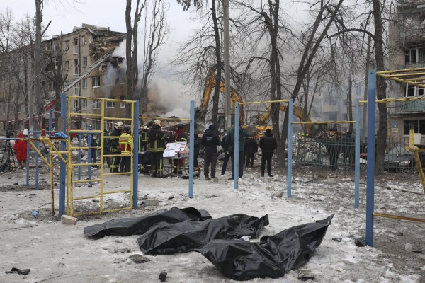 Rescuers stand near bodies retrieved from the site of a strike on a residential building in Kharkiv, northeastern Ukraine, on Saturday. Photo: EPA