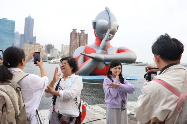 Tourists strike a pose next to a giant Ultraman inflatable displayed at Kaohsiung Wonderland during the Lunar New Year holidays in Kaohsiung, Taiwan, in February. Photo: AFP