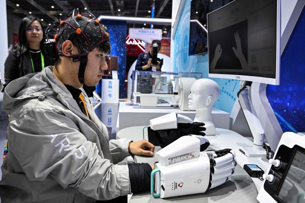 A man demonstrates a robotic hand with a brain-computer interface at the China International Import Expo on November 7, 2025.  Neuracle’s regulatory milestone underscores China’s accelerating push in neurotechnology. Photo: AFP