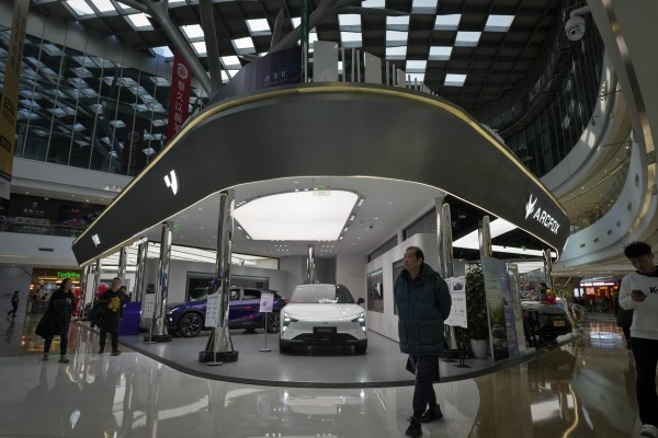 People walk past an EV showroom inside a shopping mall in Beijing. Photo: AP