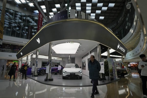 People walk past an EV showroom inside a shopping mall in Beijing. Photo: AP People walk past an EV showroom inside a shopping mall in Beijing. Photo: AP