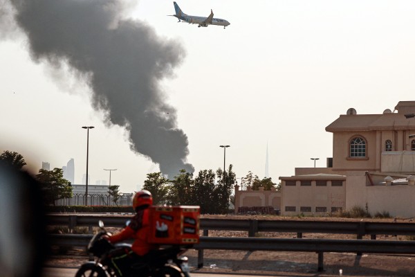 A FlyDubai aircraft prepares for landing as smoke rises from an ongoing fire near Dubai International Airport on Monday. Photo: TNS