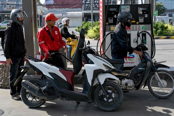 An employee (second left) pumps fuel into the vehicle of a customer in Phnom Penh, Cambodia, on March 9. Photo: AFP