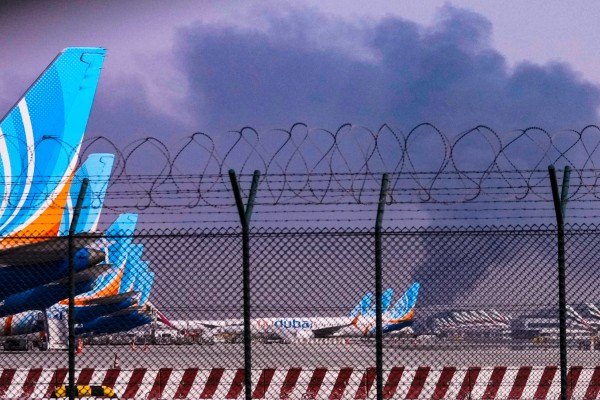 Smoke rises above aircraft parked at Dubai International Airport after a drone strike on March 16. The growing conflict in the Middle East is causing global airlines to raise fares amid a spike in jet fuel prices. Photo: AP