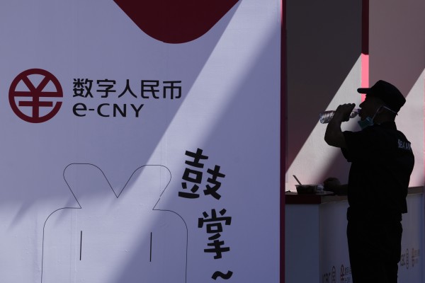 A security guard drinks from a bottle near an ad for e-CNY, or digital yuan, in Beijing on August 31, 2022. Photo: AP

