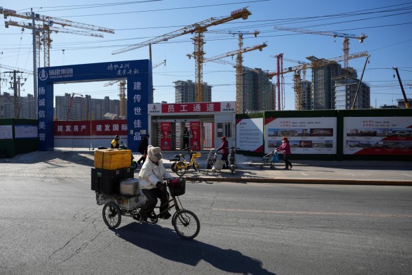 A food vendor passes a construction site in Beijing on February 8. Instead of trying to revive the property-led growth model, Beijing is patiently executing a debt migration by transferring default risks from the public to the state’s balance sheet. Photo: AP 