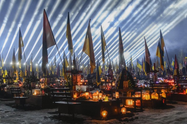 Beams of light illuminate the sky over the graves of fallen Ukrainian soldiers as friends and relatives take part in a joint prayer and candlelight vigil at Lychakiv Military Cemetery in Lviv, western Ukraine, on February 23. Photo: EPA