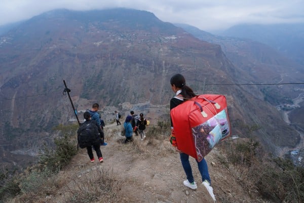 People descend a mountain with luggage as they move to new homes designed to alleviate poverty in Zhaojue county, Sichuan province, in May 2020. Photo: Xinhua People descend a mountain with luggage as they move to new homes designed to alleviate poverty in Zhaojue county, Sichuan province, in May 2020. Photo: Xinhua