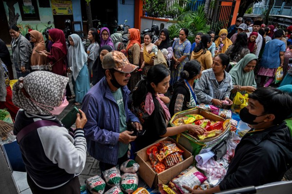 People queue in line to buy necessities at a market in Surabaya. More than 8,000 men have been denied access to public services in the city for failing to pay child support. Photo: AFP