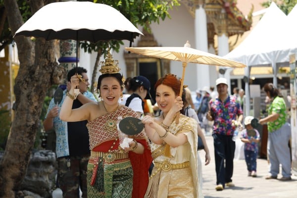 Chinese tourists wearing traditional Thai costumes shield themselves from the sun at Wat Pho, the Temple of the Reclining Buddha, in Bangkok on April 14. Photo: EPA Chinese tourists wearing traditional Thai costumes shield themselves from the sun at Wat Pho, the Temple of the Reclining Buddha, in Bangkok on April 14. Photo: EPA