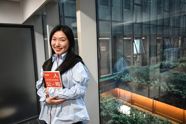 The photo taken on April 12, 2026 shows founder of SoloNest Karen Dai posing for a portrait photo with her new book “One Person Company” at a conference room in Shanghai. Young Chinese, many who fear age discrimination in their workplace after turning 35, are increasingly starting “one-person companies” that have artificial intelligence do most of the work. (Photo by Jade GAO / AFP) / TO GO WITH AFP STORY: China-AI-technology-science-employment, FOCUS by Mary YANG