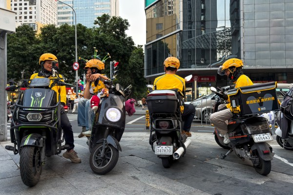 Delivery riders sit on scooters while waiting for orders at an intersection on March 24 in Shenzhen. Photo: Getty Images
