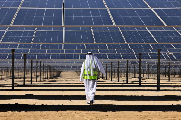 A man walks beneath solar panels at the Al Dhafra solar power project south of Abu Dhabi in 2023. Photo: AFP