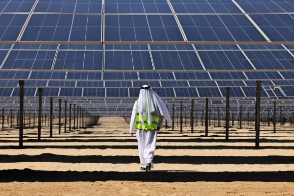 A man walks beneath solar panels at the Al Dhafra solar power project south of Abu Dhabi in 2023. Photo: AFP A man walks beneath solar panels at the Al Dhafra solar power project south of Abu Dhabi in 2023. Photo: AFP