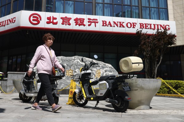 An elderly woman walks past a bank branch in Beijing on April 20. Photo: EPA An elderly woman walks past a bank branch in Beijing on April 20. Photo: EPA