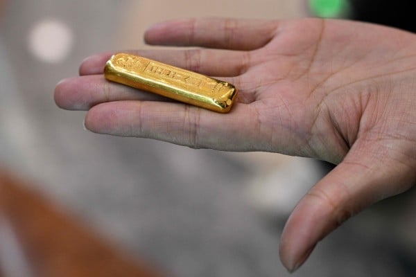A woman shows a gold bar before selling in a smart gold store machine placed in a shopping mall in Shanghai on January 29. Photo: AFP A woman shows a gold bar before selling in a smart gold store machine placed in a shopping mall in Shanghai on January 29. Photo: AFP