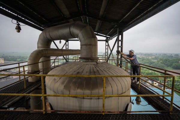 A technician works on the top deck of a distillery at Bajaj Hindustan Sugar factory that produces ethanol in August 2023. Photo: AP A technician works on the top deck of a distillery at Bajaj Hindustan Sugar factory that produces ethanol in August 2023. Photo: AP