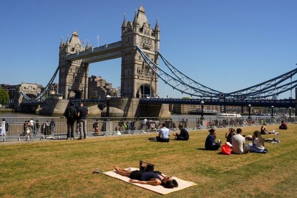 Londoners bask in the sunshine near the British capital’s Tower Bridge. Photo: AP