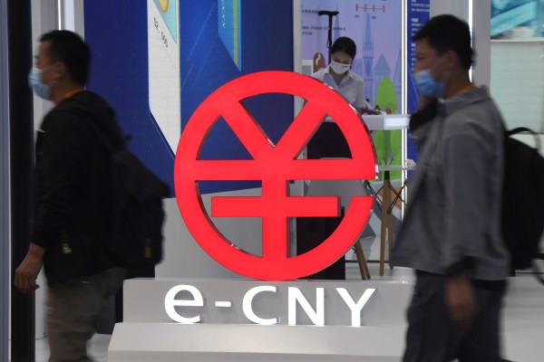 People walk past a sign promoting the digital yuan, or e-CNY, at an expo in Beijing. Photo: Xinhua
