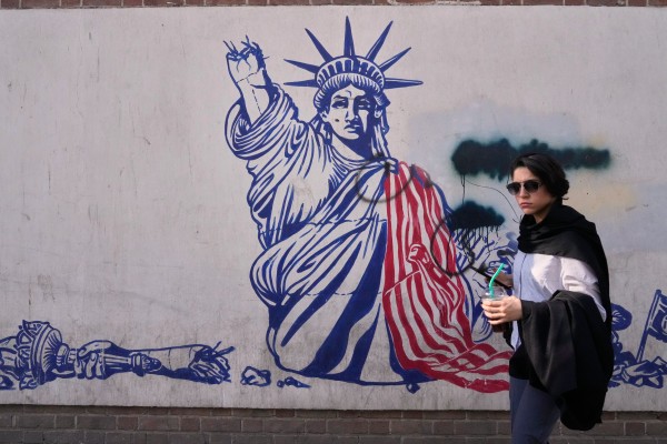 A woman walks past an anti-American mural on the wall of the former US Embassy, now a museum, in Tehran. Photo: AP