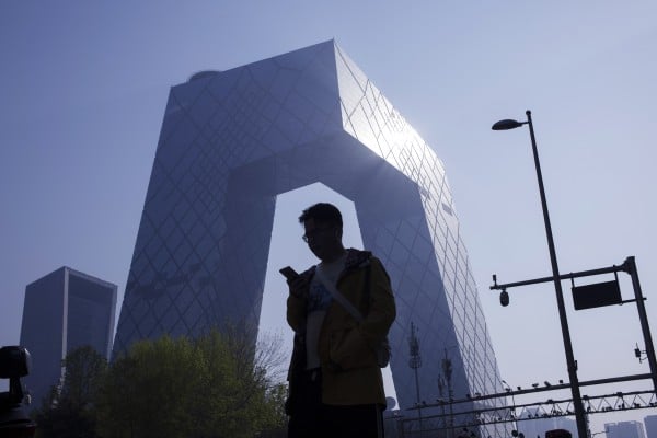 A man checks his phone while walking in Beijing’s central business district. Photo: EPA-EFE A man checks his phone while walking in Beijing’s central business district. Photo: EPA-EFE