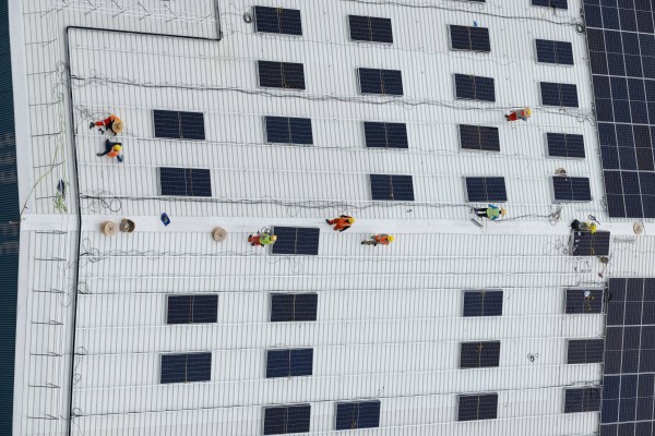 Workers install solar panels on the roof of a warehouse near Jurong Island in Singapore last year. Photo: AFP