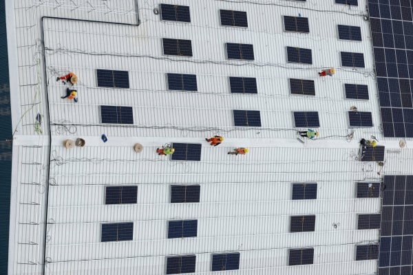 Workers install solar panels on the roof of a warehouse near Jurong Island in Singapore last year. Photo: AFP Workers install solar panels on the roof of a warehouse near Jurong Island in Singapore last year. Photo: AFP