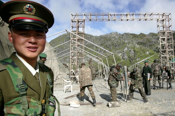 A Chinese soldier stands guard while Indian troops work at the Nathu La Pass in July 2006. Photo: AP