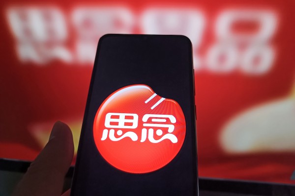An internet user views the Synear Food webpage on his computer in the background with the company logo displayed on his phone. The company has been blacklisted by Washington for allegedly using forced labour. Photo: Getty Images