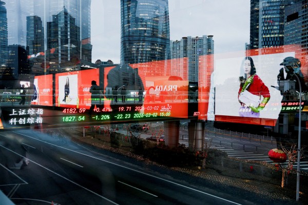 An electronic board shows Shanghai stock indices as people walk on a pedestrian bridge in the Lujiazui financial district in Shanghai on March 2. Photo: Reuters