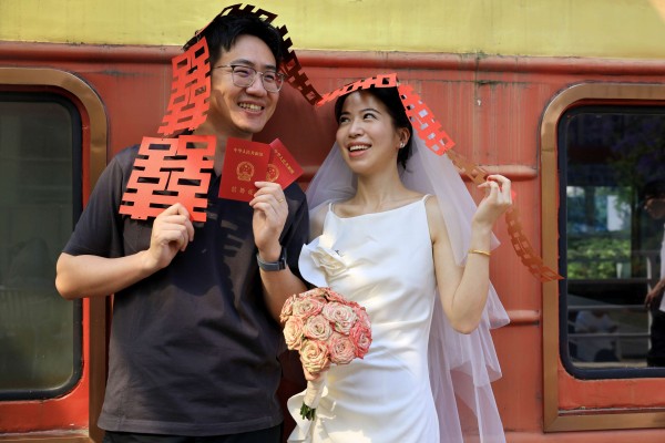 A newly-wed couple pose for a photo with their marriage certificates at a marriage registration office on May 20 in Chengdu, Sichuan province, China. Photo: Getty Images