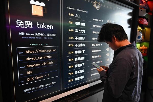 A customer uses his phone in front of a board with the menu at AGI Bar in Beijing. Drinkers at the AI-themed bar in the city's tech district can even plug in to DeepSeek for free. Photo: AFP