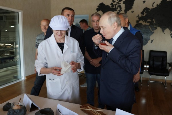 Russian President Vladimir Putin tries caviar during his visit to a fish processing complex on the Southern Kuril Island of Iturup on August 13. Photo: Sputnik via Reuters