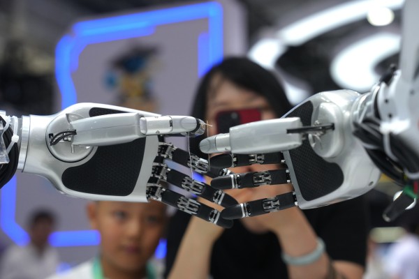Onlookers watch a robot thread a string through a needle during the World Robot Conference in Beijing on Wednesday. Photo: AP