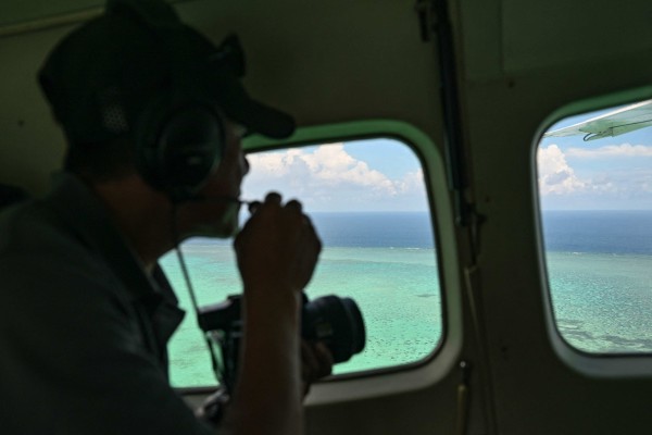 A Philippine coastguard personnel talks on a mic as he looks over Scarborough Shoal in the disputed South China Sea in June. Photo: AFP