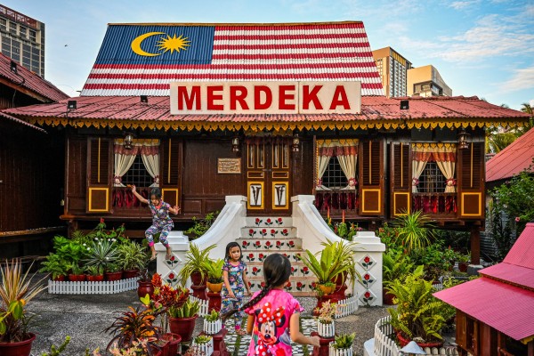 Children play outside a traditional Malay wooden house in Melaka city. Photo: AFP