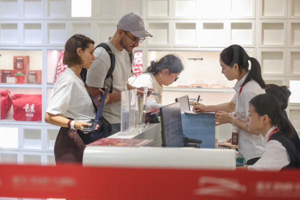Foreign tourists handle their smartphones while buying tickets for a performance at a theatre in China’s Chongqing municipality last month. Photo: Xinhua